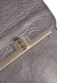 Šedá kožená peňaženka s textúrovaným povrchom, vybavená kovovou sponou s akcentmi geometrického dizajnu.