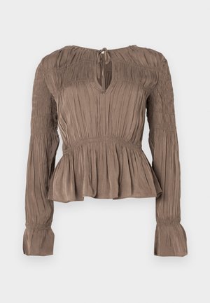 Brun peplumtopp med långa ärmar, rynkdetaljer på axlar och muddar, nyckelhålsringning och texturerat tyg.