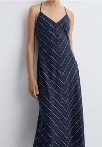 Námořnická modrá maxi šaty bez rukávů s výstřihem do V, zdobené bílými chevron pruhy a s nastavitelnými ramínky. Měkká, hladká textilie.