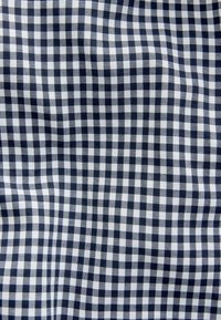 Țesătură gingham în nuanțe de bleumarin și alb, cu un model în carouri; textură netedă, material ușor, având pătrate de dimensiuni egale.