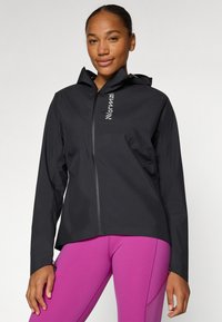 Schwarze, leichte, kapuzenjacke mit einem Frontreißverschluss. Merkmale ein elegantes Design, elastische Bündchen und Belüftungsdetails. Kombiniert mit pinken Leggings.