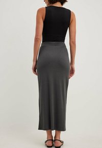 Černý bezramínkový top spárovaný s šedou žebrovanou maxi sukní, která má přiléhavý střih a hladkou texturu. Jednoduchý, minimalistický design.