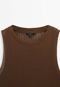 Haut marron sans manches en maille côtelée avec un col rond et une étiquette de marque visible à l’arrière du col.