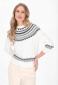 Maglione bianco lavorato a maglia con motivi geometrici neri sul collo e sui polsini. Presenta un collo rotondo e maniche a tre quarti.