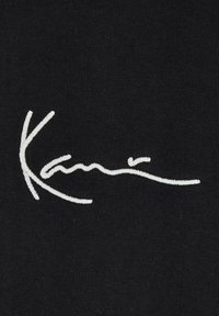 Black fabric featuring white embroidered text in a cursive style reading "Kani." The texture is smooth with a slight ribbing pattern.