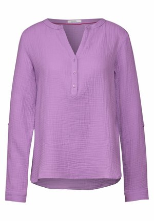Camisa de manga larga, con botones, en tejido texturizado de color púrpura claro con escote en V, que presenta un ajuste holgado y un dobladillo ligeramente curvado.