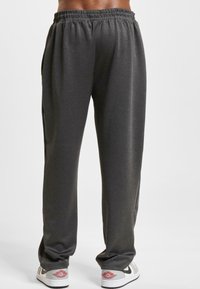 Grå træningsbukser med elastisk talje, to sidelommer og lige ben-design. Stoffet ser glat og letvægtsagtigt ud.