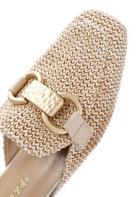 Zapato slip-on beige tejido con punta cuadrada, acento de herrajes dorados y un acabado texturizado con forro interior suave y liso.