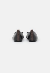 Zwarte leren schoenen met een vlak design, veter sluiting en een bruine patroon hakaccent met een logo. Soepele textuur.