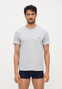 Lys grå bomulls t-skjorte med kort erme, har en liten rød "HUGO" logo på brystet, kombinert med mørkeblå boxershorts.