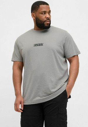 Graues Baumwoll-T-Shirt mit kurzen Ärmeln und rundem Halsausschnitt, mit einem schwarzen Logo-Print auf der Brust, kombiniert mit schwarzen Cargo-Hosen.