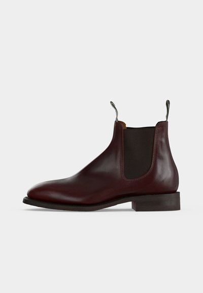 Bottine Chelsea en cuir marron foncé avec panneau latéral élastique, talon bas et languettes à l'avant et à l'arrière.