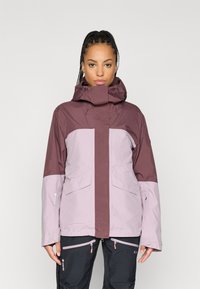 Vesitli vedenpitävä takki tummassa purppurassa ja vaaleassa laventelissa. Varustettu korkealla kauluksessa, säädettävällä hupussa ja etutaskuilla. Rakenteellinen kangas, tyylikäs muotoilu.