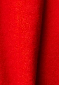 Roter Stoff mit einer weichen Textur, der ein glattes, gestricktes Design zeigt. Die Farbe ist lebhaft, mit subtilen Schattierungs- und Tiefenunterschieden.