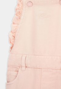 Lichtroze denim salopette met ruches op de schouderbanden, drukknoopjes, voorzakken en geborduurd merkembleem. Gladde textuur, casual ontwerp.