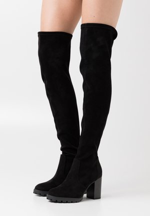 Bottes en daim noir au-dessus du genou avec un talon bloc épais, présentant un design ajusté et une surface texturée, idéales pour gagner en hauteur.