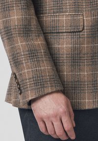 Brązowa marynarka w kratę, wykonana z teksturowanej tkaniny, z klapami typu notch i trzema ciemnymi guzikami na rękawie.