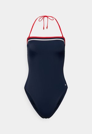 Tmavomodré jednodielne plavky s červenými remienkami dookola okolo krku, bielym lemom pozdĺž výstrihu, hladkou textúrou a vysokým strihom nohavičiek.