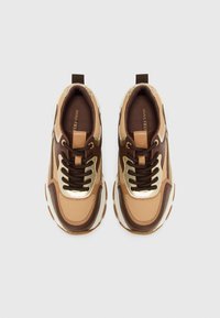 Suedet - og mesh-sneakers i nuancer af brun og beige, med gyldne accenter og robuste snørebånd, samt en polstret sål og struktureret design.
