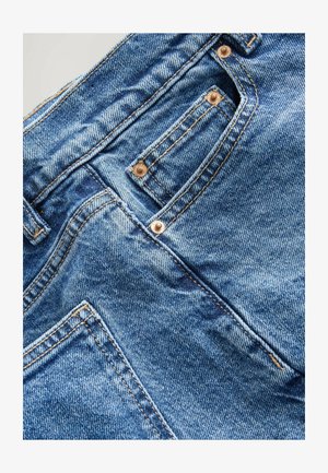 Jeans in denim con un colore blu sbiadito, con accessori in tonalità dorata, cuciture sottili e un piccolo dettaglio sulla tasca anteriore.