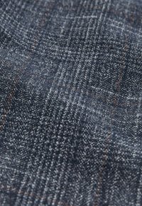 Sötétkék denim szövet, amely finom kockás mintával, fehér és narancssárga fonalakkal rendelkezik, texturált felülettel és puha befejezéssel.