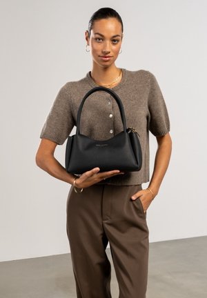 Sac en cuir noir avec une silhouette structurée, deux poignées arrondies et un subtil logo doré. La surface texturée renforce l'intérêt visuel.