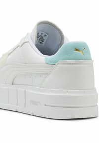 Fehér Puma sneaker világoskék velúr sarkú, arany Puma logóval és vastag, strukturált talppal, hátulról nézve.