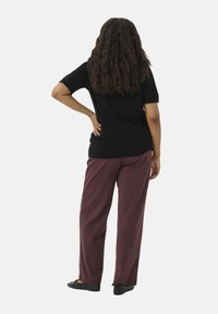 Sort kortærmet top parret med bordeaux vidde bukser. Outfittet har en afslappet pasform, set fra ryggen, med sorte slip-on sko.