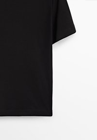 Svart kortärmad t-shirt i mjuk bomull, med en avslappnad passform och rak nederkant, utan synliga mönster eller dekorationer.