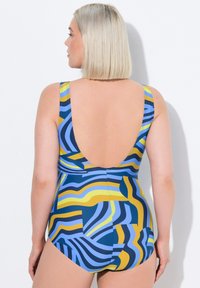 Maillot de bain une pièce avec un motif abstrait de vagues bleu, jaune et marine ; décolleté plongeant à l'arrière et larges bretelles pour le soutien. Texture lisse.