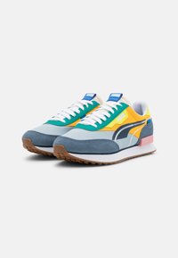 Farbenfrohe Sneaker, die eine Mischung aus blauen, grünen, gelben und grauen Materialien zeigen. Wildleder- und Mesh-Konstruktion mit weißen Schnürsenkeln und Gummilaufsohle.