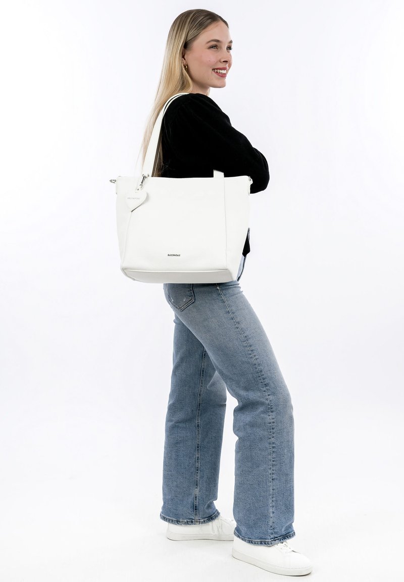 Bolso tote de cuero blanco con forma rectangular, asas superiores y una etiqueta decorativa en forma de corazón. Textura suave con mínima marca.