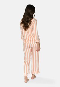 Set di pigiama a righe di un arancione pallido con orlo arricciato su maniche e pantaloni. Tessuto morbido con vestibilità comoda e maniche lunghe.