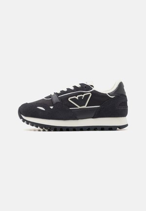 Black athletic shoe with suede and mesh upper, white accents, lace-up design, and a textured sole for traction. Logo on side panel.