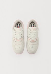 White and light pink sneakers with a smooth leather upper, perforated toe, padded collar, flat laces, and logo detail on the tongue.