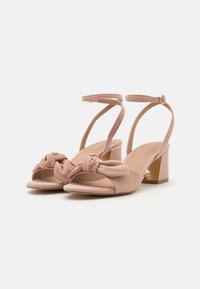 Rosa Wildleder Sandalen mit Absatz, einem geknoteten Vorderdesign, offener Zehenpartie und Knöchelriemen, ausgestattet mit einem Blockabsatz mit metallischem Akzent.
