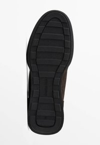 Svart gummisula med texturerade räfflor, fäst vid en brun överdel. Designen har en slät yta och en diskret präglad varumärkeslogotyp.