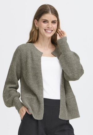 Oliven grøn strikket cardigan med åbent front, ribbet tekstur, lange ærmer og sidelommer, stylet over en hvid top.