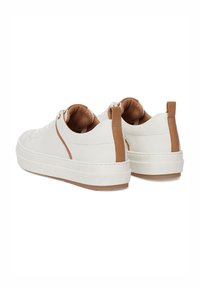 Białe sneakersy z teksturowaną powierzchnią, brązowe akcenty na pięcie i grubą białą podeszwą. Sznurowadła są widoczne z przodu.