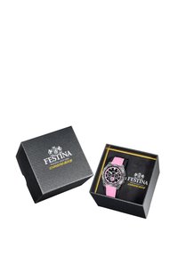 Montre avec un bracelet en caoutchouc rose, un cadran noir, des accents en argent et des marqueurs d'heure détaillés, présentée dans une boîte-cadeau noire texturée.