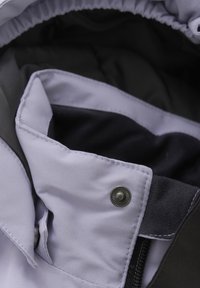 Ljuslila jacka med svart foder, som har en tryckknappsstängning och slät textur, med snygg sömnad och design.