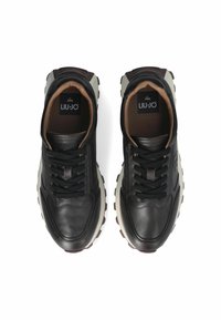 Sneakers in pelle nera con accenti beige, punta tonda e suola in gomma spessa. Presentano lacci e un logo sulla linguetta.