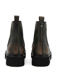 Brązowe skórzane botki za kostkę z chropowatym wykończeniem, kontrastującą czarną grubą podeszwą oraz pętelkami z tyłu ułatwiającymi zakładanie.