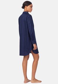 Navy-blaues Hemdkleid mit langen Ärmeln, Knopfmanschetten und einem geschwungenen Saum. Hergestellt aus einem glatten Stoff, mit einem klassischen Kragen und seitlichen Schlitzen.