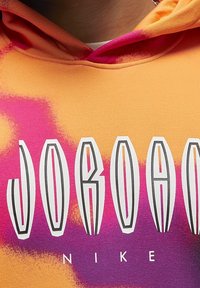 Felpa con cappuccio arancione con motivi tie-dye rosa e viola, con la scritta grande "JORDAN" in bianco e nero sopra "NIKE."