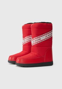 Piros, párnázott téli csizmák vastag fekete talppal, átlós fehér sávval, amelyen az "LOVE MOSCHINO" felirat olvasható. Simább anyag, kerek forma.