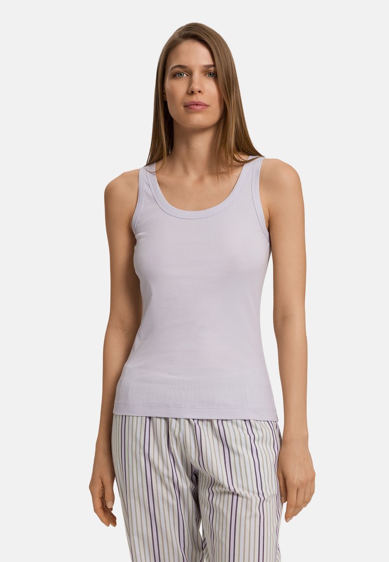 Světle fialový tílko vyrobené z vyplétané látky, s kulatým výstřihem a přiléhavým střihem. V kombinaci s pruhovanými pyžamovými kalhotami.