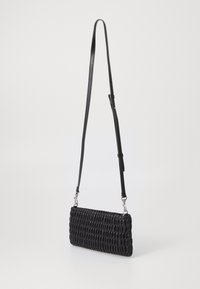 Černá tkaná textilní crossbody taška s dlouhým nastavitelným popruhem a stříbrnými kovovými detaily. Kompaktní obdélníkový tvar, hladký kožený povrch.