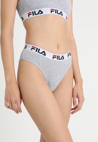Slip di cotone grigio con una vita elastica bianca che presenta il logo Fila in nero e rosso. Il slip ha un design a taglio alto e una texture liscia.