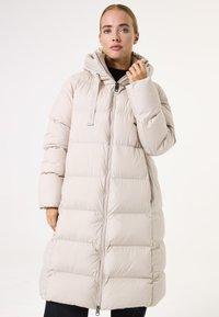 Abrigo largo acolchado beige con capucha, que presenta un cierre frontal, puños elásticos y distintivos cuadros verticales para aislamiento y textura.